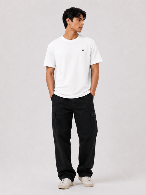 Full body view of a male model wearing the white 6SENSE by ROKURA oversized t-shirt with relaxed black cargo trousers.