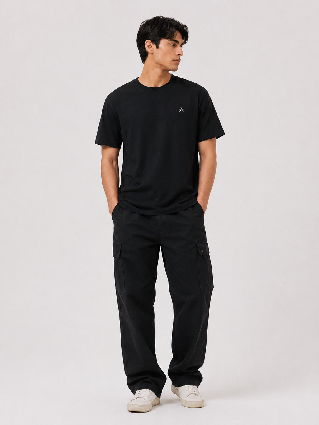 Full body view of a male model wearing the BLACK 6SENSE by ROKURA oversized t-shirt with relaxed black cargo trousers.